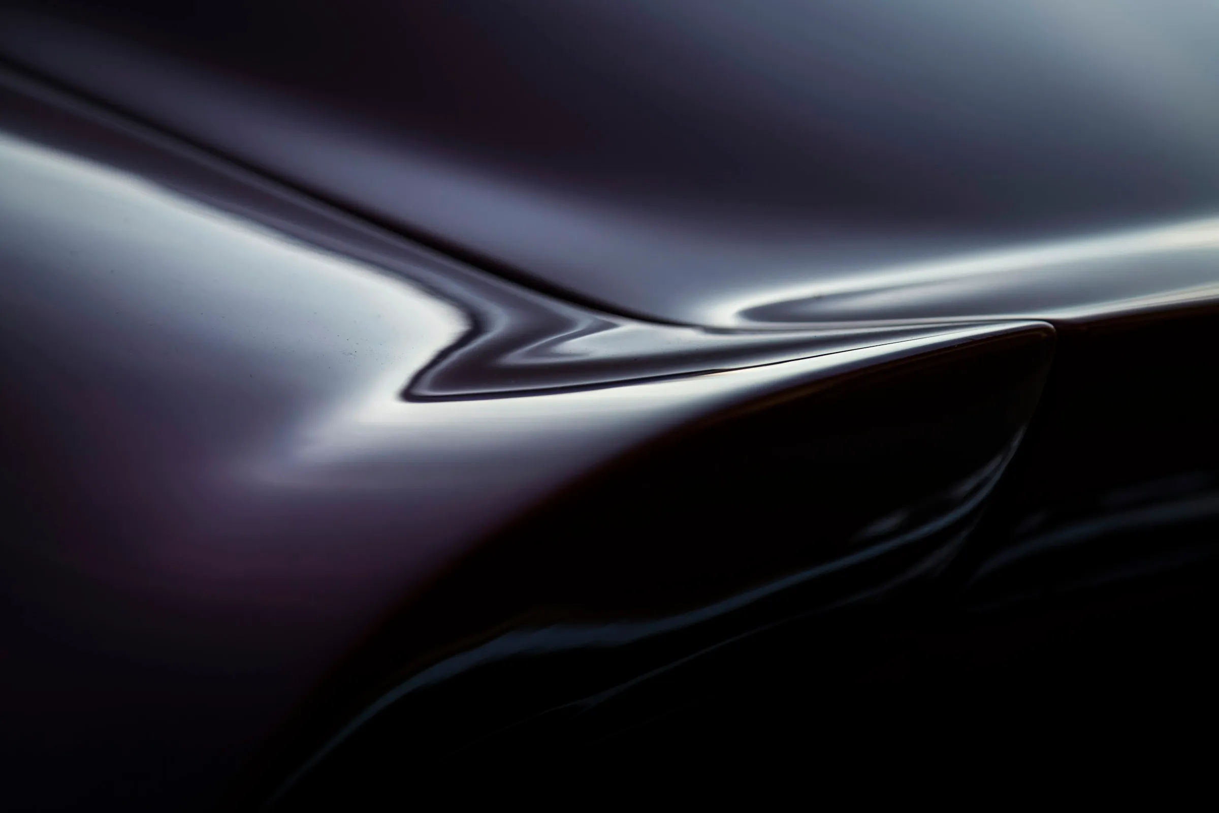 Close-up of the curve of a glossy black car body.