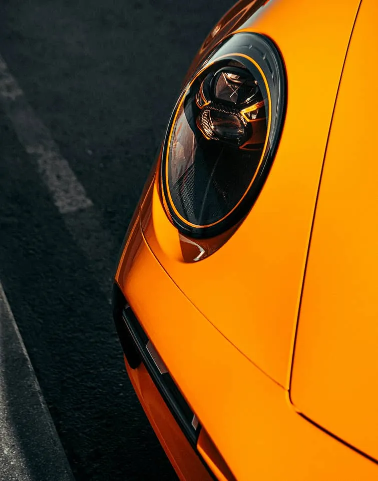 Phare d’une sportive orange, en gros plan.