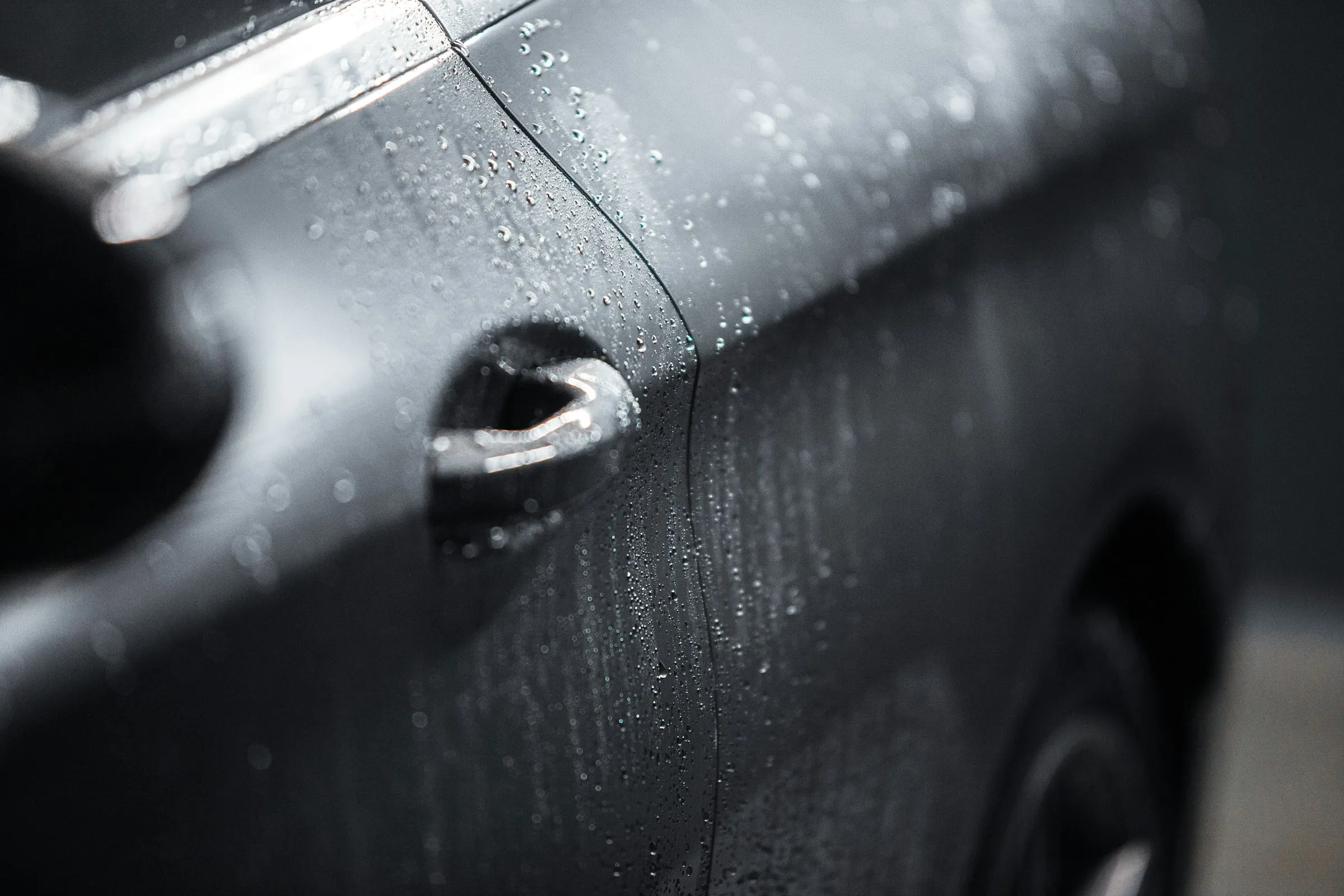 Gouttes de pluie sur une portière noire.
